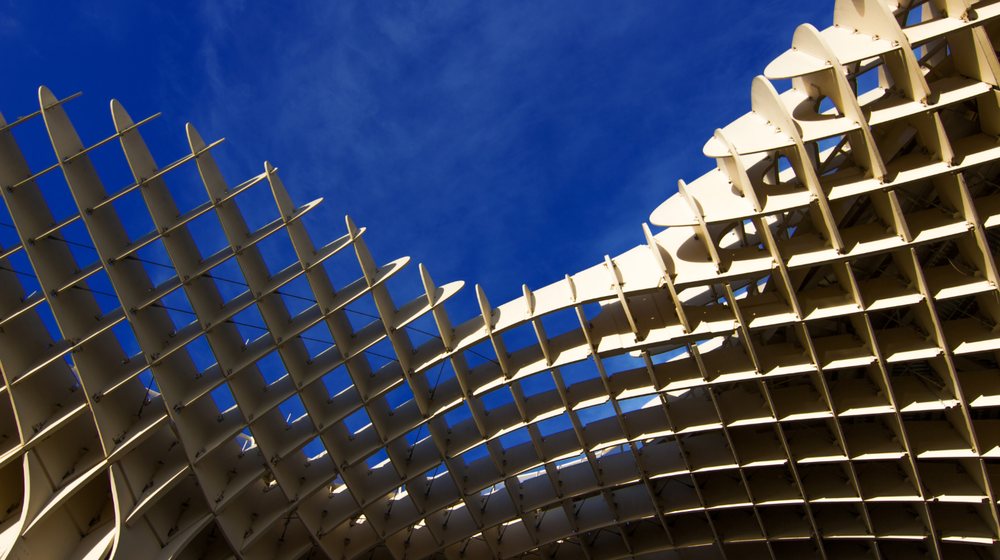 Estructura reticular de madera vista a contraluz contra el cielo